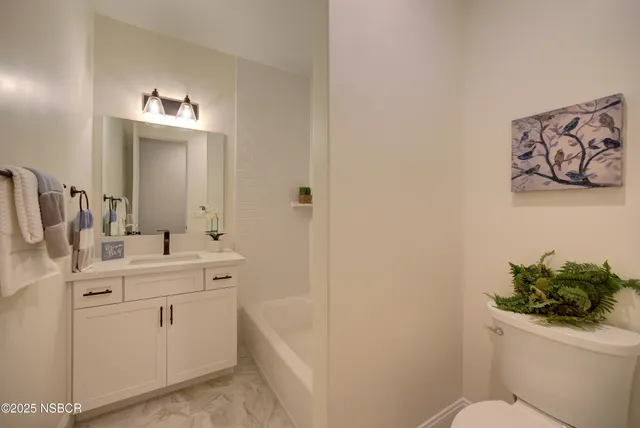 a bathroom with a toilet sink vanity and mirror