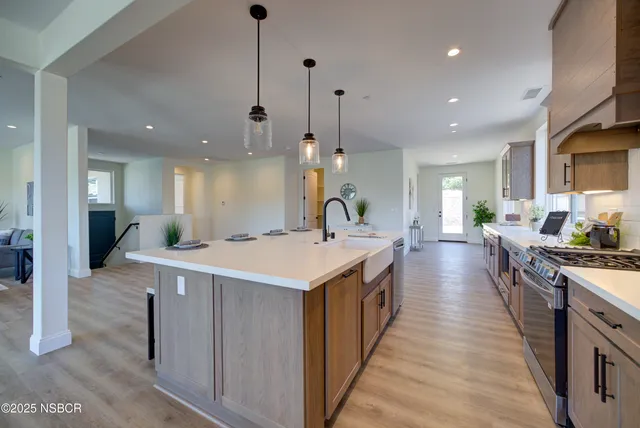 a large kitchen with kitchen island a stove a sink a refrigerator and a dining table