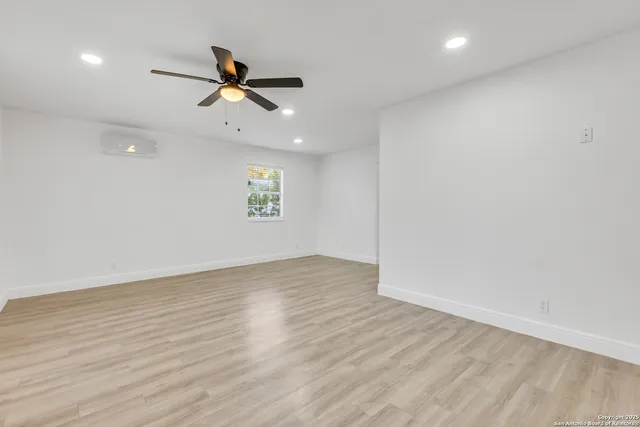 an empty room with wooden floor ceiling fan and windows
