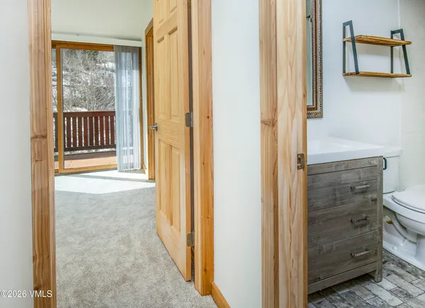 a view of a hallway with wooden floor and a bathroom