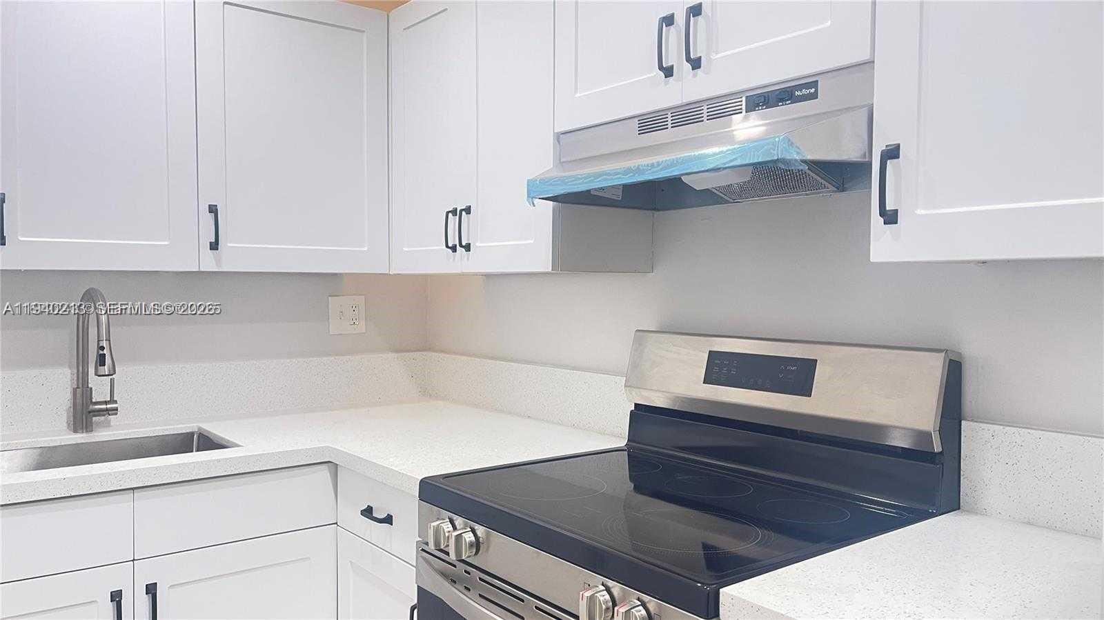 200 South Birch Road, Unit 702 Fort Lauderdale, FL 33316 - Photo 7 of 19 a kitchen with white cabinets and white appliances