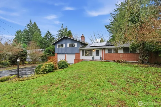 a view of a yard in front of a house with large windows