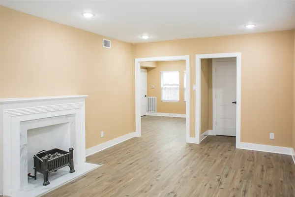 a view of a hallway with wooden floor and a bathroom