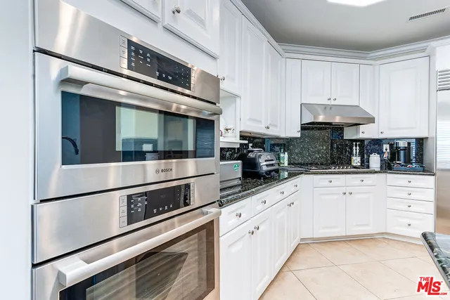 a kitchen with stainless steel appliances white cabinets a sink and a stove