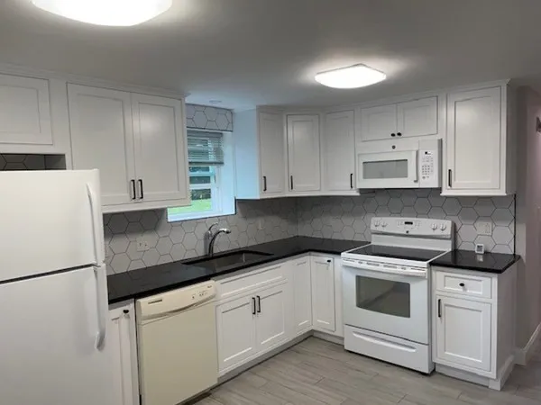 a kitchen with white cabinets white appliances and sink