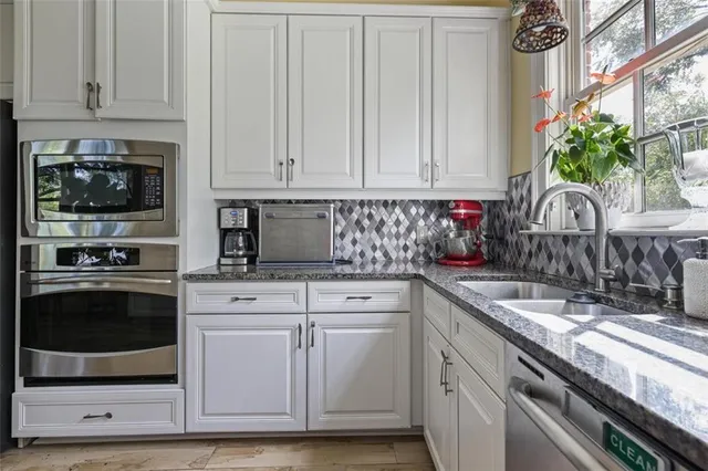 a kitchen with granite countertop a sink stainless steel appliances and cabinets