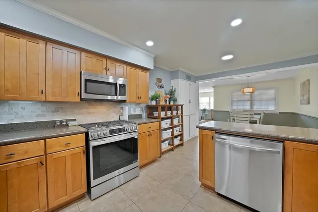a kitchen with stainless steel appliances granite countertop a stove top oven a sink dishwasher and a microwave oven with cabinets