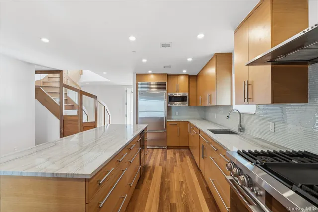 a large kitchen with stainless steel appliances granite countertop a large window and a sink