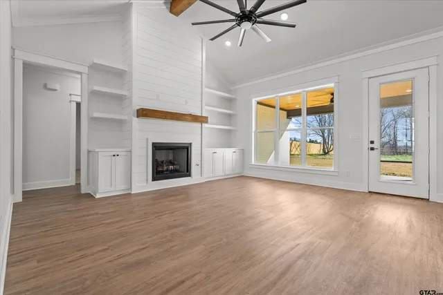 a view of an empty room with a window and wooden floor