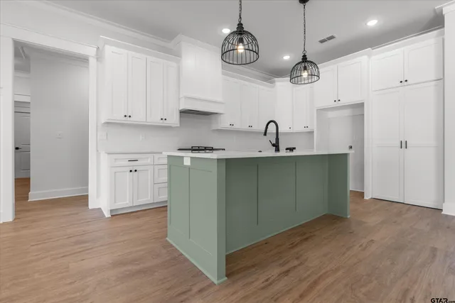 a kitchen with kitchen island stainless steel appliances a sink cabinets and wooden floor