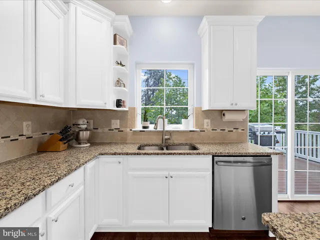 a kitchen with granite countertop a sink window and cabinets