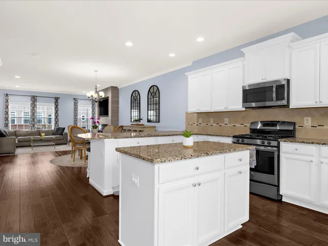 a kitchen with stainless steel appliances granite countertop a stove top oven a sink dishwasher and a microwave oven with wooden floor