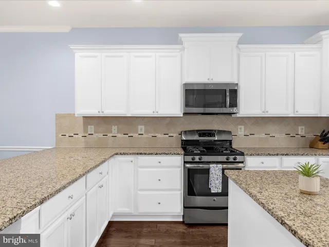 a kitchen with granite countertop white cabinets and black stainless steel appliances