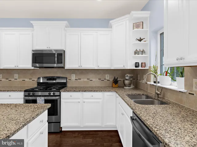 a kitchen with stainless steel appliances granite countertop a sink stove and microwave
