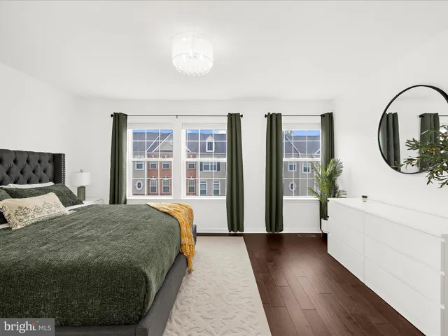 a spacious bedroom with a bed a mirror and a large window