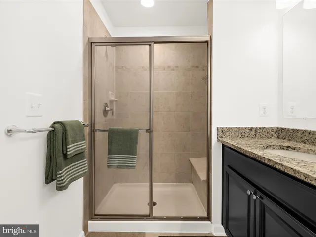 a bathroom with a granite countertop shower a mirror and a sink