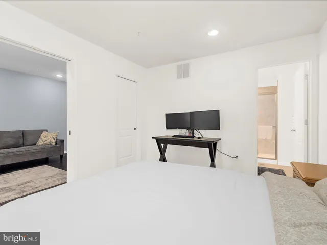 a bedroom with a bed a chair and a potted plant on dresser