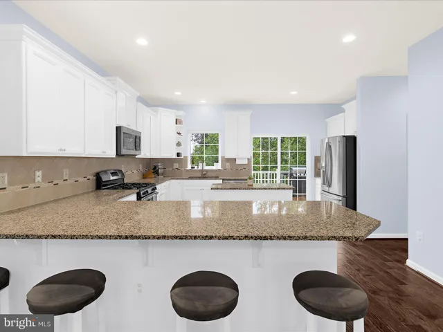 a kitchen with stainless steel appliances granite countertop a sink a stove a window and a counter space