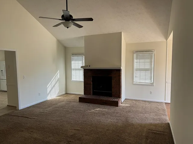 a view of an empty room with a fireplace and a window