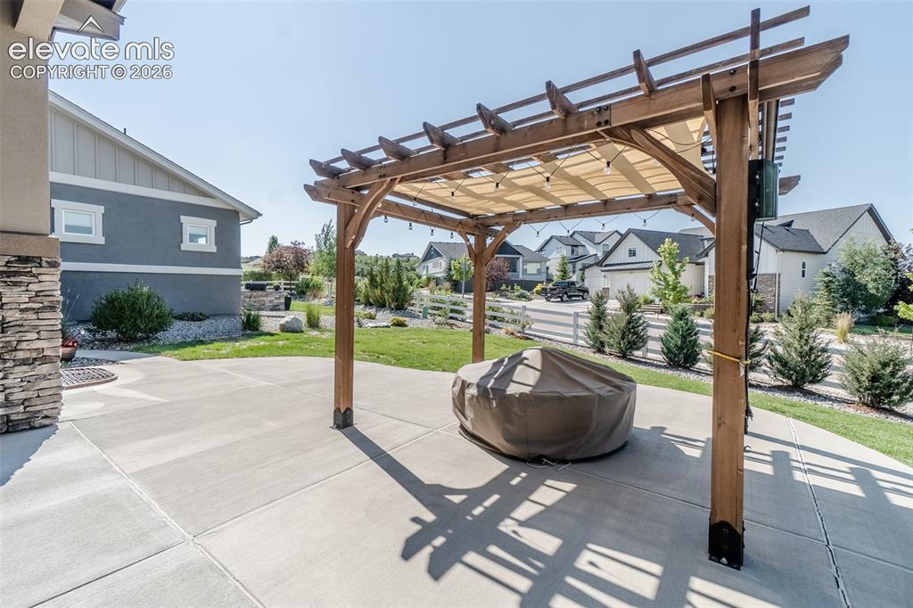 1061 Native Dancer Terrace Colorado Springs, CO 80921 - Photo 31 of 50 Expansive concrete patio featuring a wooden pergola with a retractable shade canopy and string lighting
