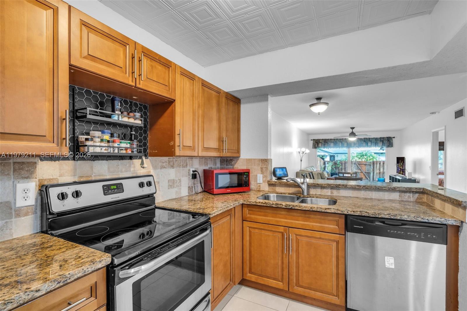 3785 Raleigh Street Hollywood, FL 33021 - Photo 14 of 36 a kitchen with stainless steel appliances granite countertop a stove a sink and a microwave