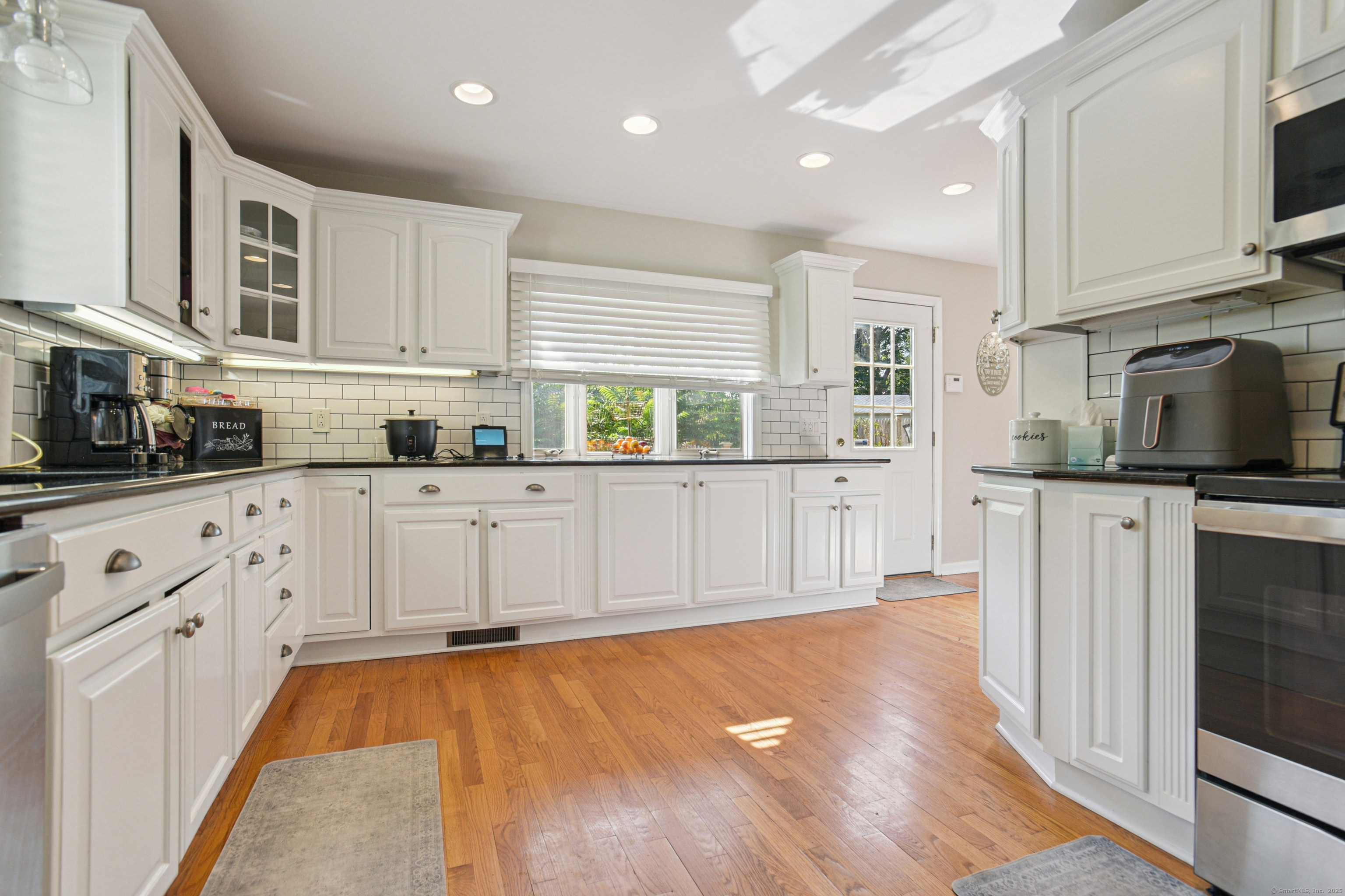 a kitchen with stainless steel appliances granite countertop a stove a sink and white cabinets