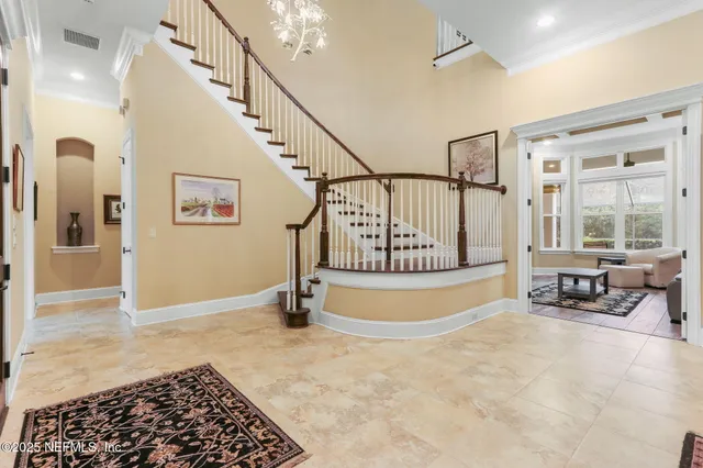 a view of a dining room with furniture a chandelier and large windows