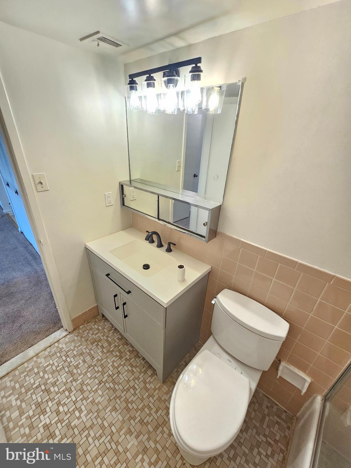 9900 Georgia Avenue, Unit 415 Silver Spring, MD 20902 - Photo 18 of 25 a bathroom with a sink and mirror with toilet