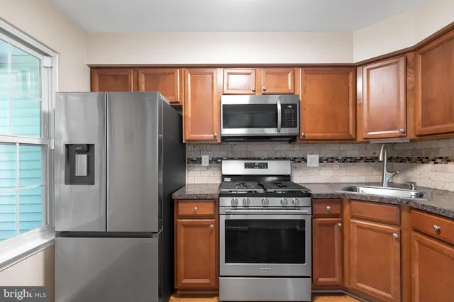 a kitchen with stainless steel appliances granite countertop a refrigerator stove and microwave