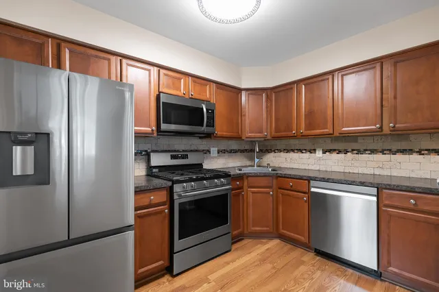 a kitchen with stainless steel appliances granite countertop a stove top oven a refrigerator and a microwave