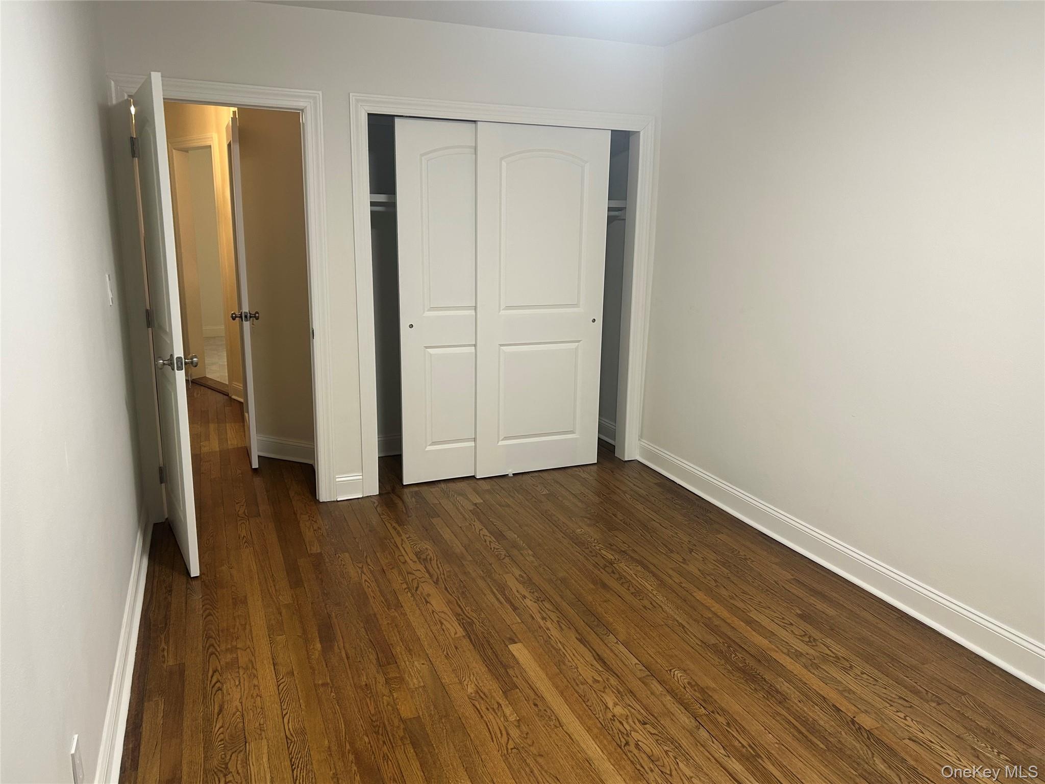 133-25 Blossom Avenue, Unit 1 Queens, NY 11355 - Photo 8 of 8 Unfurnished bedroom with dark wood-style flooring and a closet
