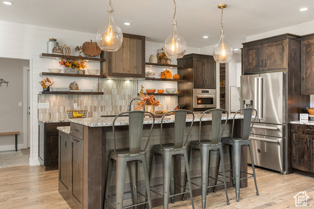 1192 East Ashdown Road Cedar City, UT 84721 - Photo 29 of 96 Kitchen with dark wood-finish cabinetry, stainless steel appliances, a multi-level island with a light-toned countertop, and wood-finish flooring