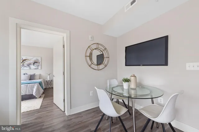 a dining room with wooden floor a glass table and chairs