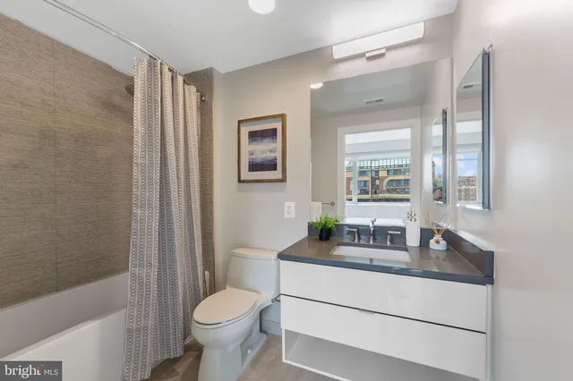 a bathroom with a granite countertop toilet sink and mirror