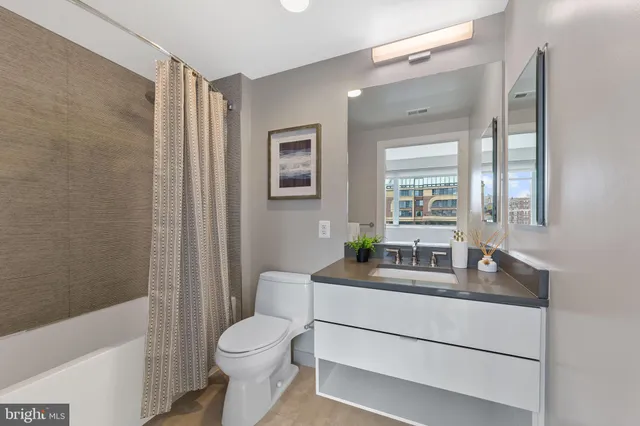 a bathroom with a granite countertop toilet sink and mirror
