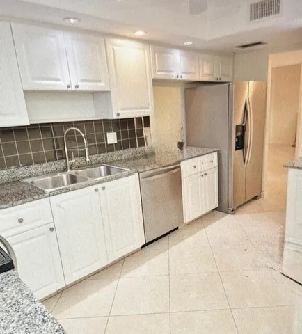 a kitchen with stainless steel appliances granite countertop a sink and a refrigerator