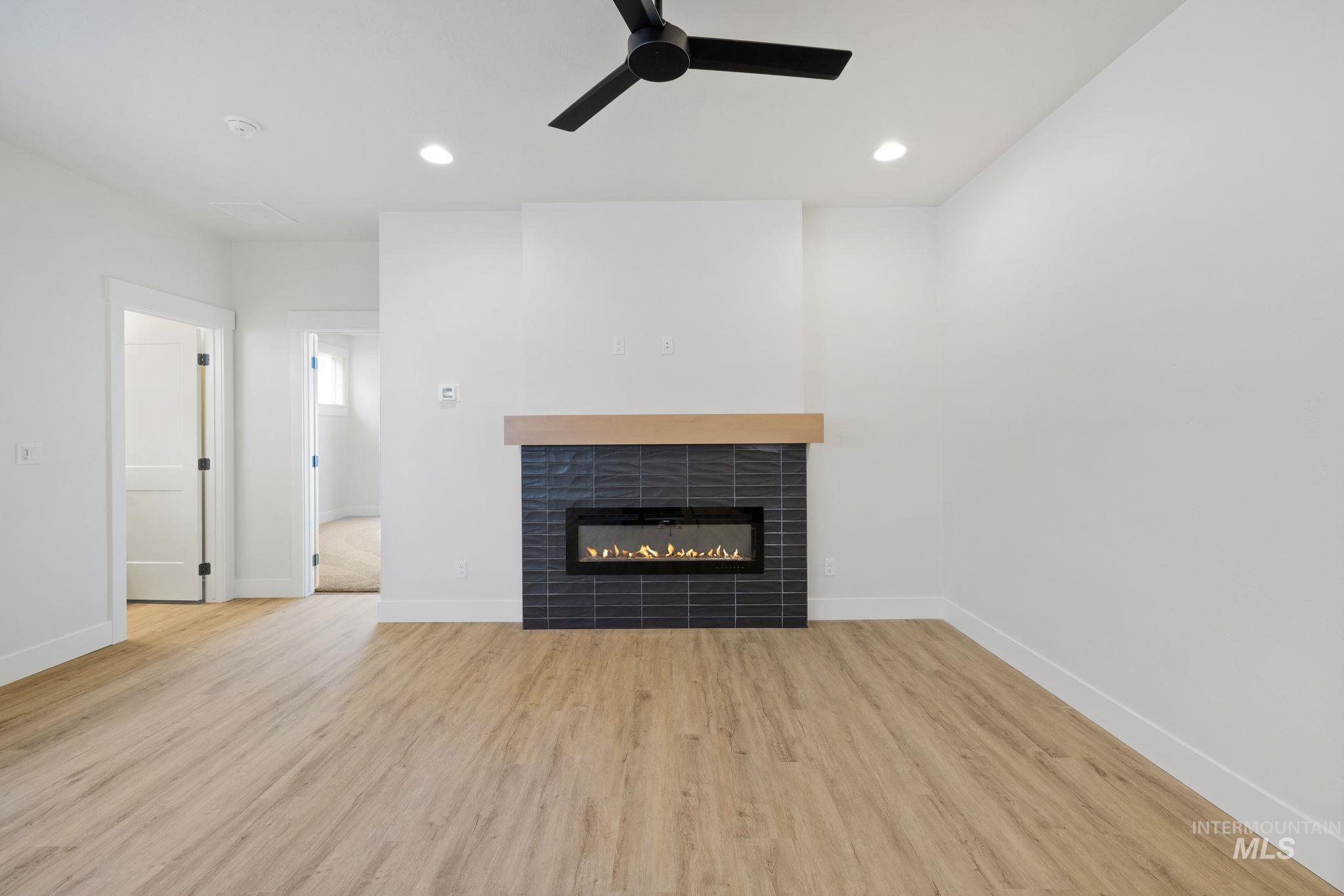18 Ogden Street Cascade, ID 83611 - Photo 15 of 39 Unfurnished living room featuring light wood finished floors, recessed lighting, a tile fireplace, and ceiling fan