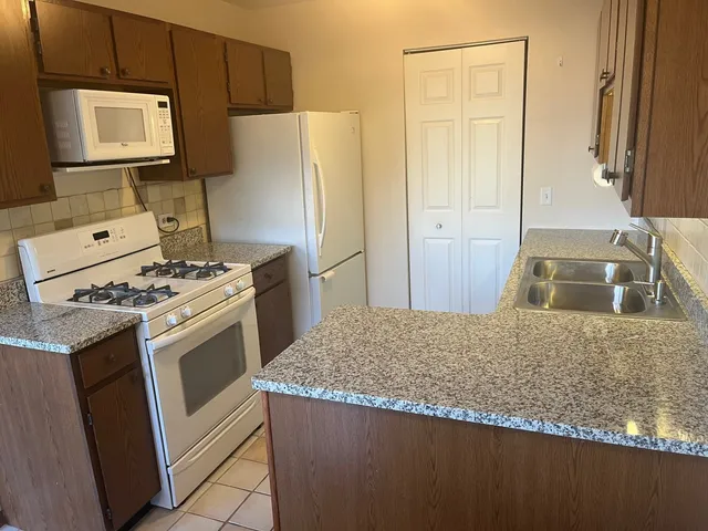 a kitchen with granite countertop a refrigerator stove and sink