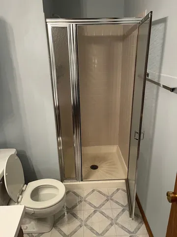 a bathroom with a glass door shower and toilet