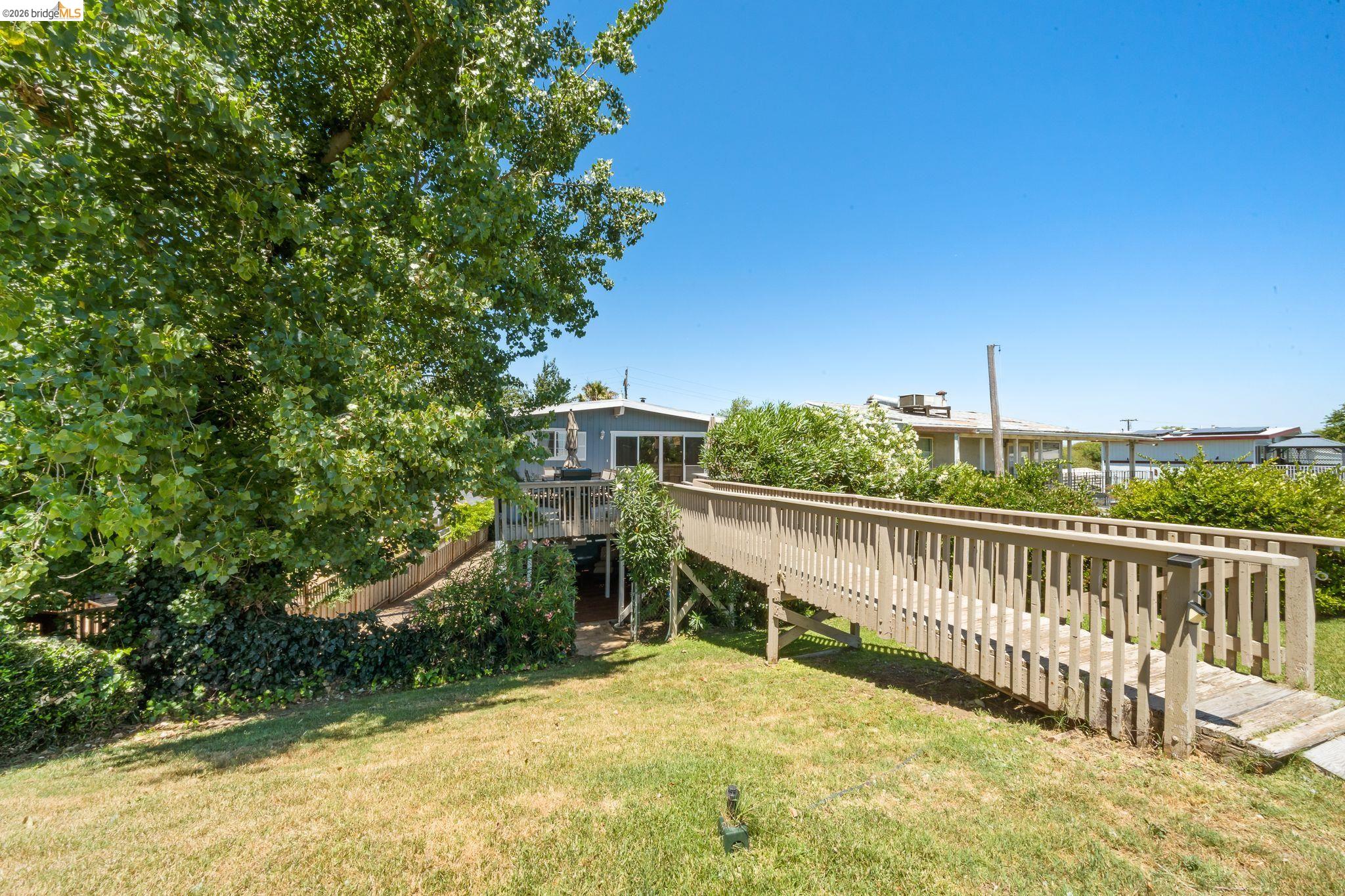 1704 Taylor Road Bethel Island, CA 94511 - Photo 55 of 73 Expansive grassy yard with mature trees and a wooden ramp leading to a deck