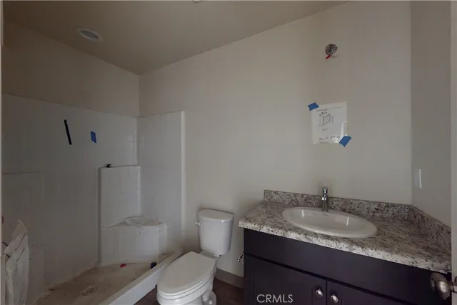 a bathroom with a granite countertop sink a toilet and shower