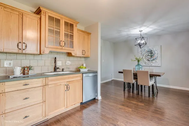 a kitchen with cabinets wooden floor dining table and chairs