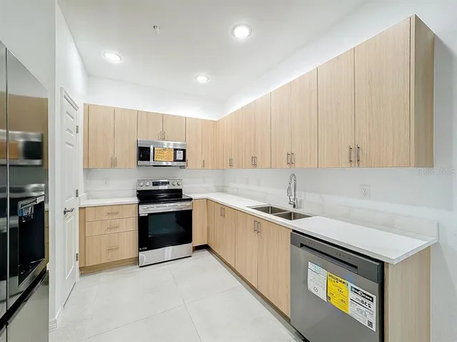 a kitchen with stainless steel appliances granite countertop a sink and dishwasher a stove top oven with white cabinets