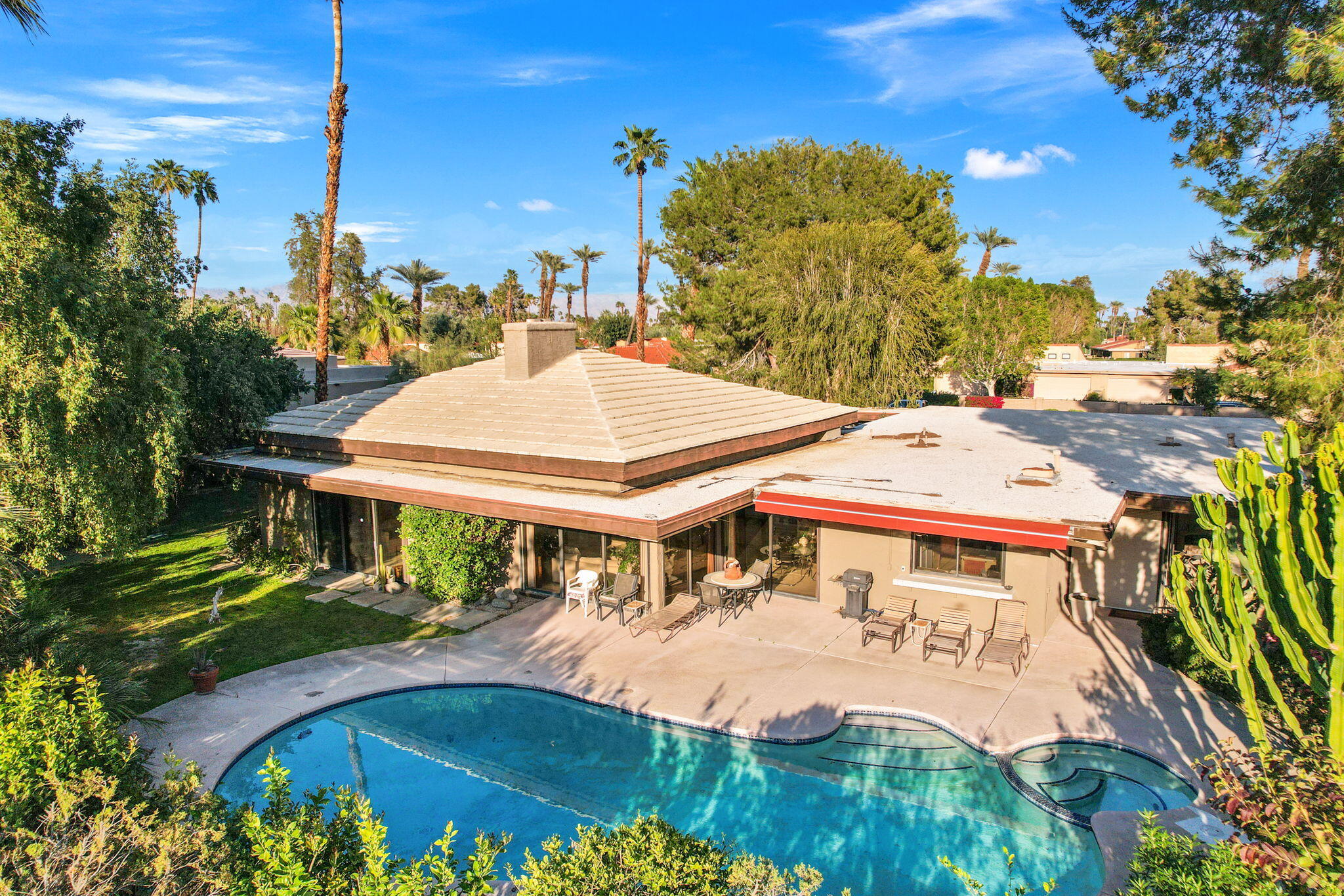 40675 East Thunderbird Terrace Rancho Mirage, CA 92270 - Photo 10 of 58 a view of a white house with a swimming pool lawn chairs and a fire pit