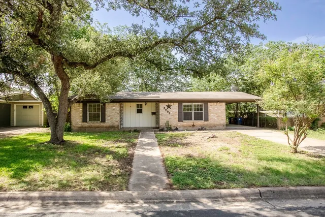 a view of a yard in front of a house with large tree
