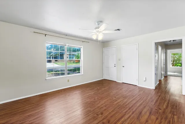 a view of an empty room with wooden floor and a window