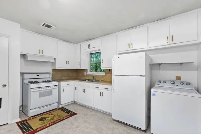 a kitchen with a sink a stove a refrigerator and white cabinets