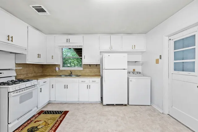 a kitchen with white cabinets and white appliances