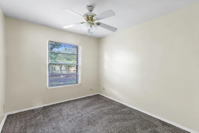 an empty room with a chandelier fan and windows