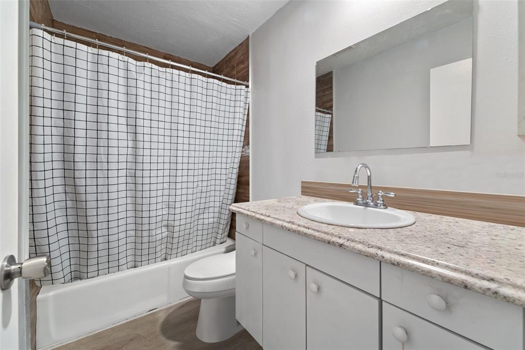 1112 Longfellow Road Sarasota, FL 34243 - Photo 36 of 48 a bathroom with a granite countertop toilet a sink a mirror and shower curtain